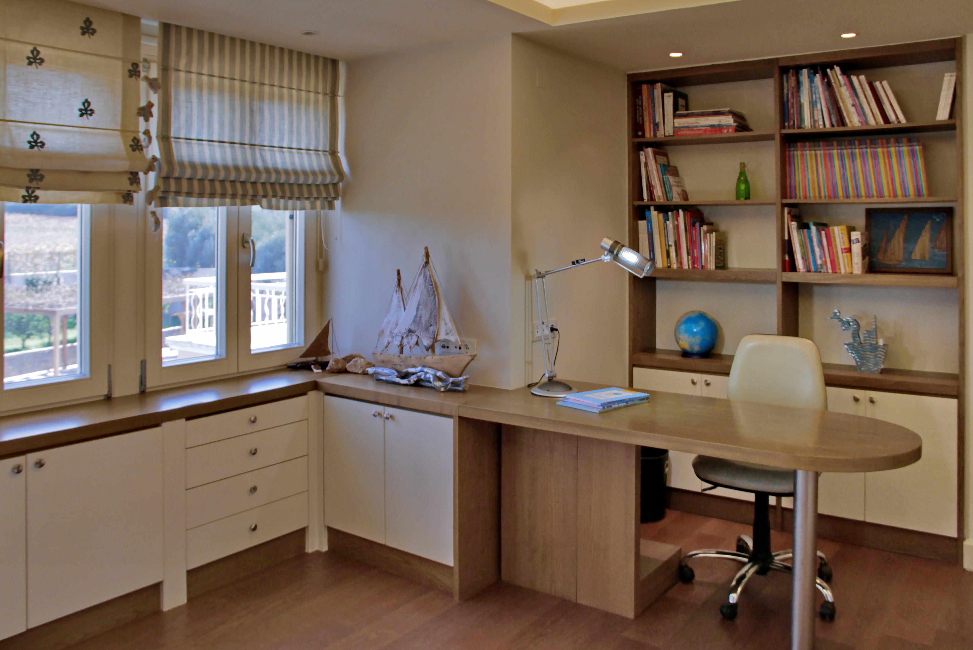 A study with a desk, chair, bookshelf, and a window with curtains.