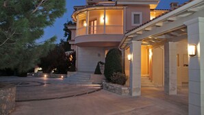 A two-story house with a balcony, stone steps, and a driveway. - Villa Metaxas (Malevizi)