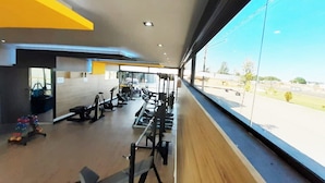 Une salle de sport équipée de divers appareils d’exercice, dotée de grandes fenêtres et offrant une vue sur l’extérieur.