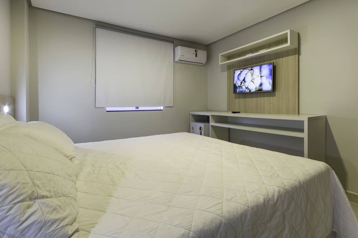 Habitación de hotel con una cama grande, un televisor montado en la pared y un escritorio integrado.