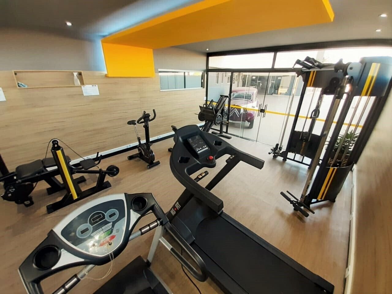 A gym with cardio equipment, weight machines, and a mirrored wall.