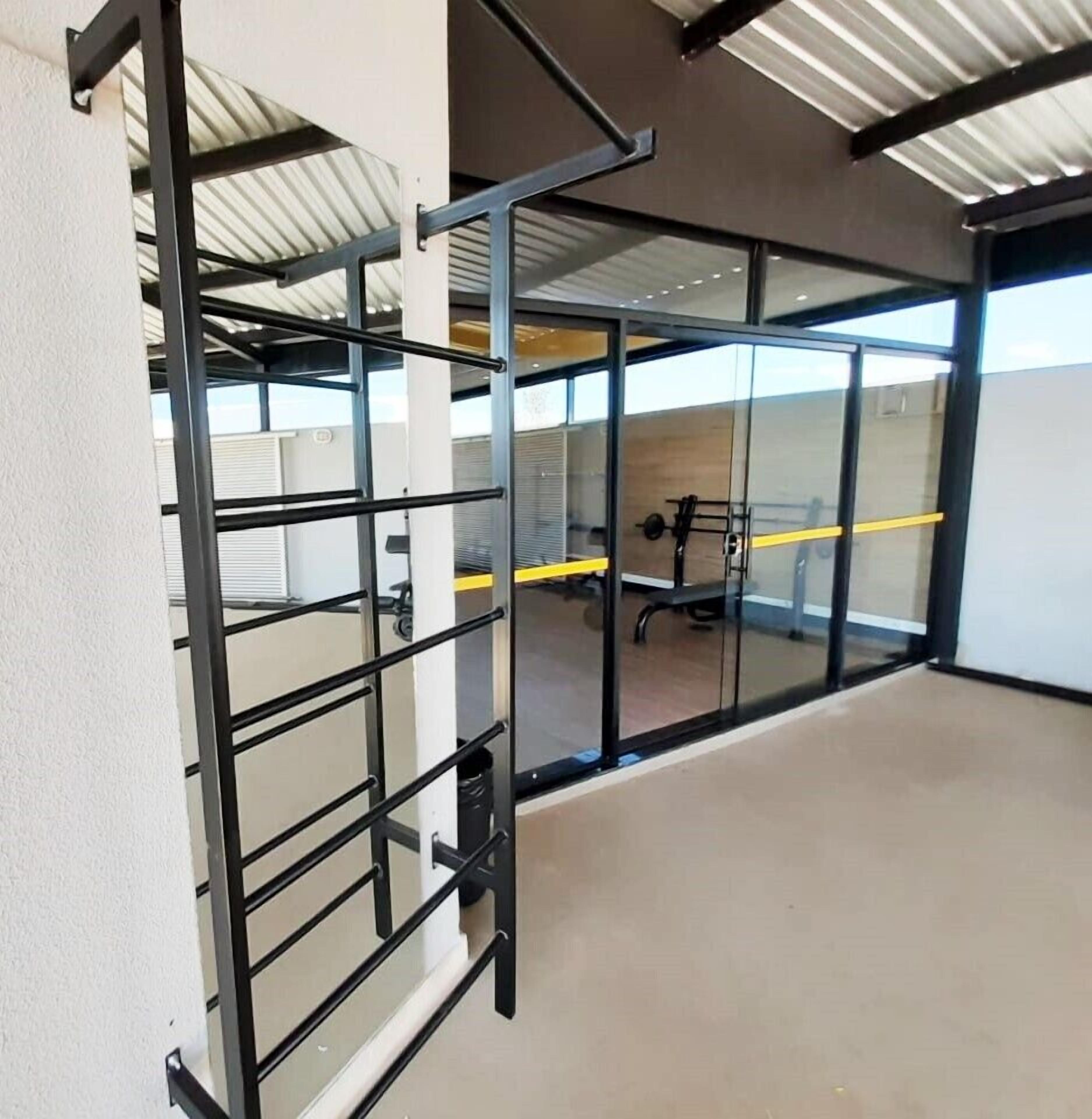 Um espaço de escritório moderno com divisórias de metal, parede de vidro e piso de concreto.