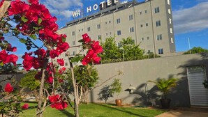 Un hôtel avec une enseigne indiquant « WR HOTEL » devant un bâtiment doté de nombreuses fenêtres et d’un toit plat.