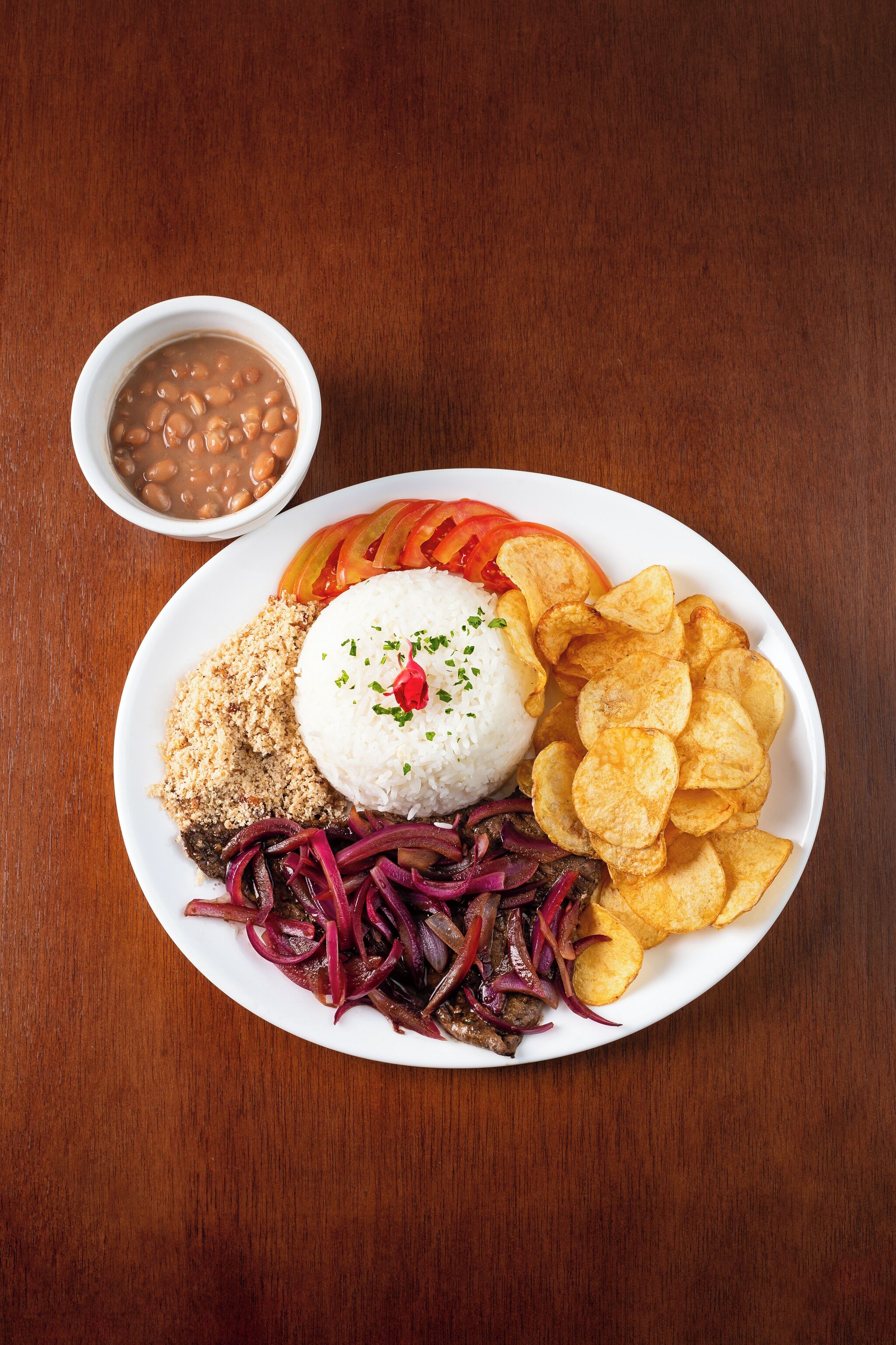 Un plato de comida con arroz, frijoles, totopos y una ensalada.