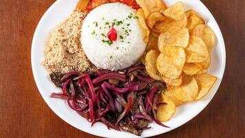 Un plato de comida con arroz, frijoles, totopos y una ensalada.