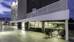 Un hôtel moderne doté d’un bar et d’un espace de restauration sur le toit, avec un design épuré et contemporain, un toit plat et de grandes fenêtres.