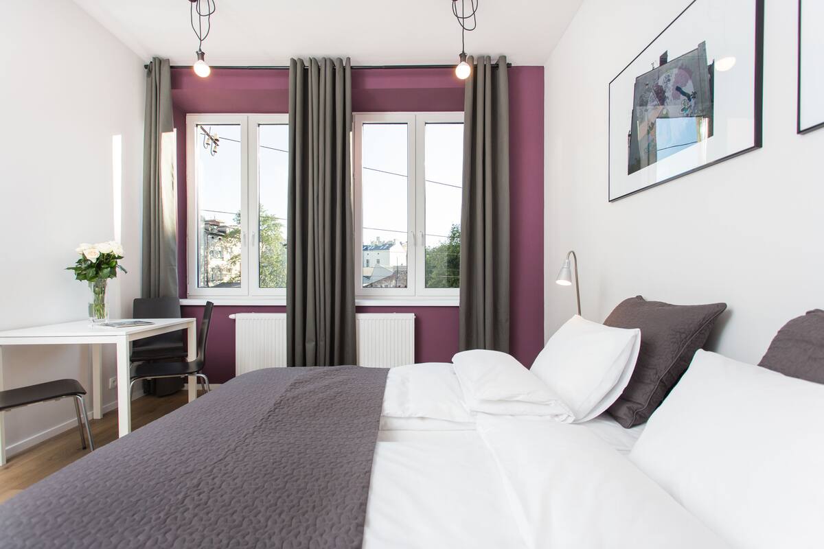 Una habitación de hotel moderna con una cama grande, un escritorio y una ventana con cortinas.