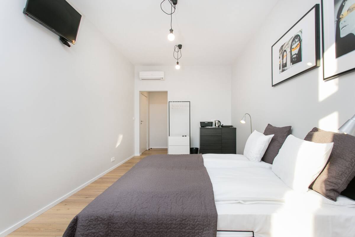 Un dormitorio moderno con cama, mesitas de noche, armario y televisor de pantalla plana montado en la pared.
