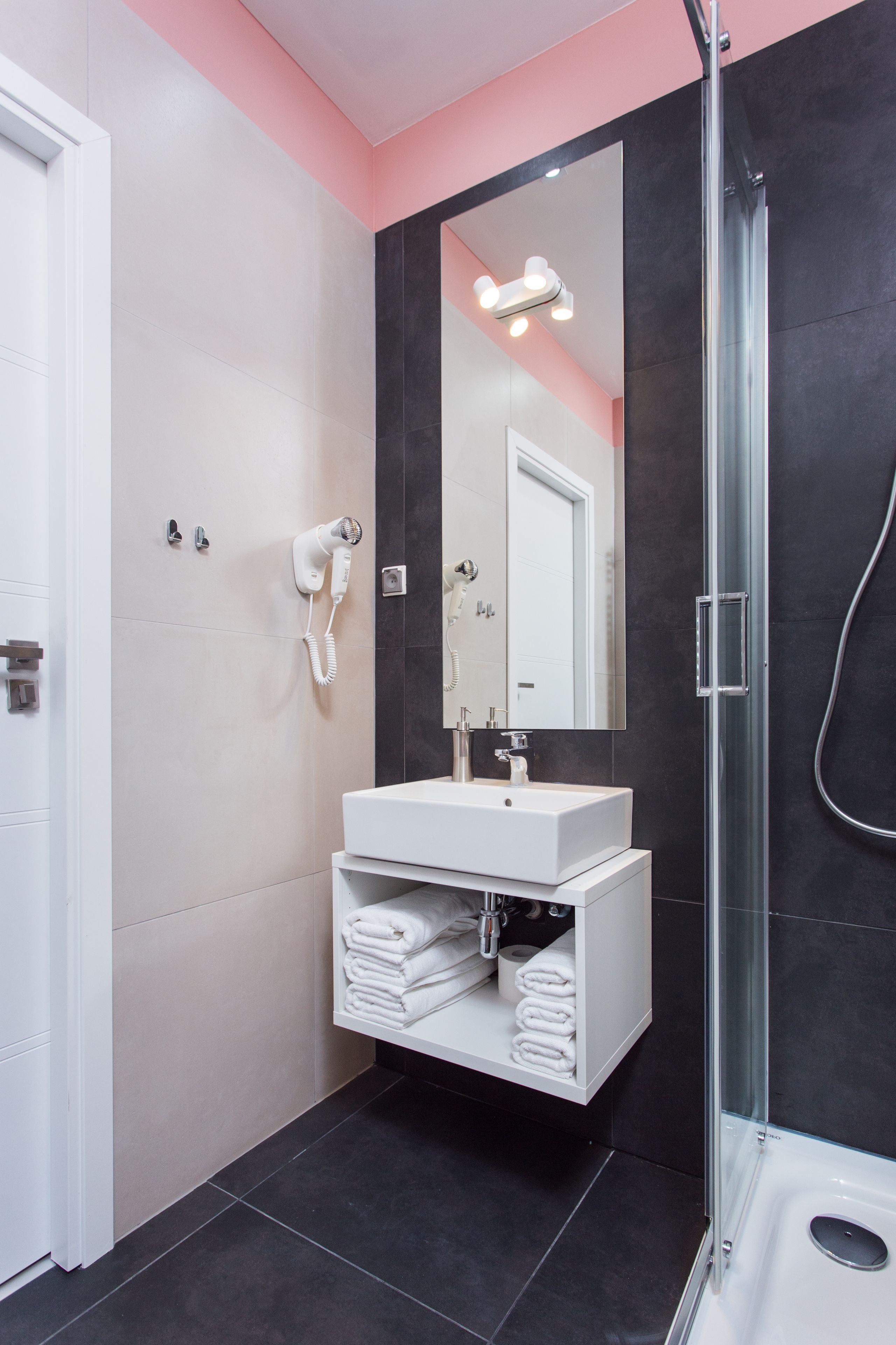 A modern bathroom with a glass-enclosed shower, a white sink, and a mirror above it.