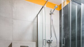 Un baño moderno con ducha envuelta en vidrio, inodoro y lavamanos.