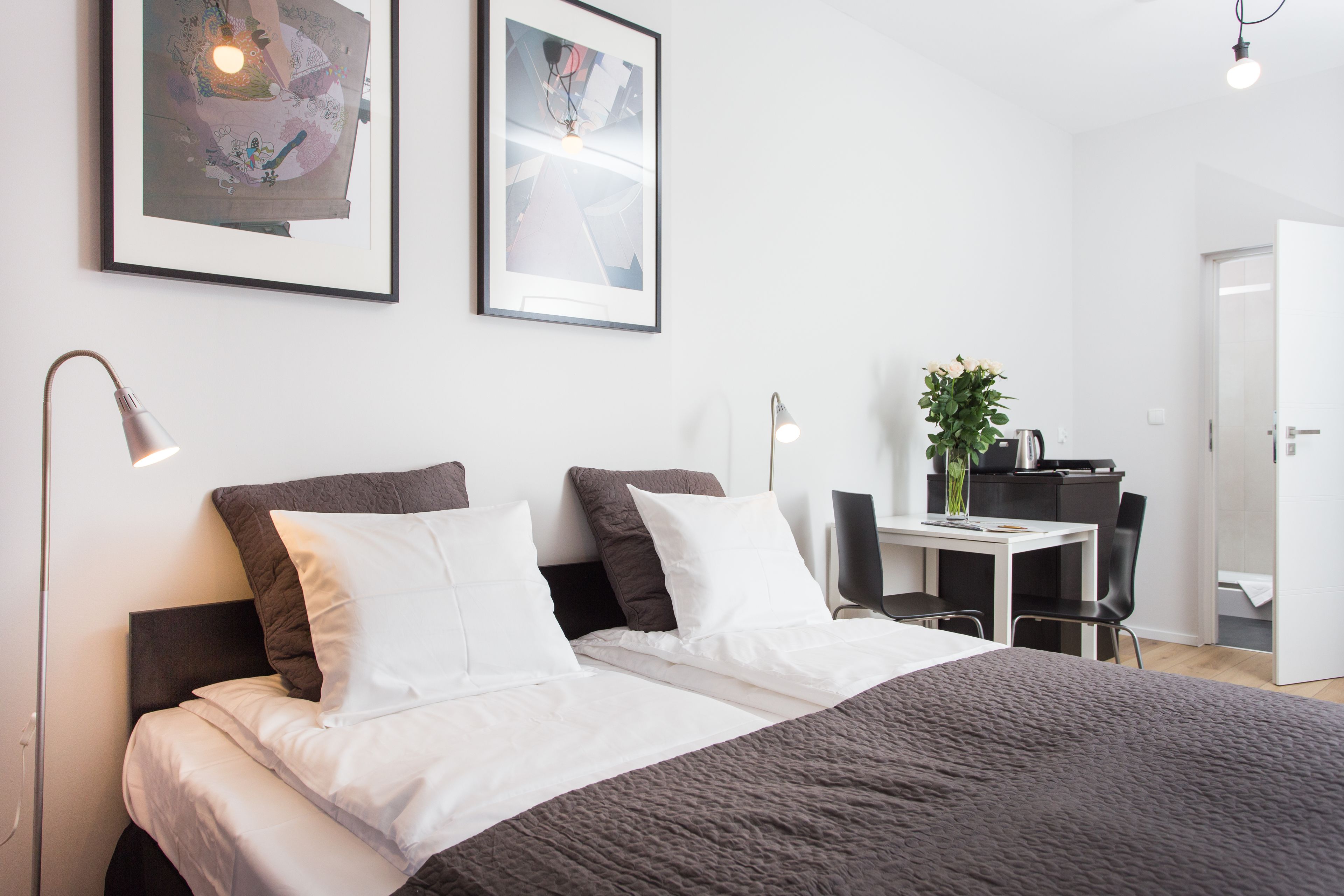 Una habitación de hotel moderna con una cama grande, un escritorio y dos cuadros en la pared.