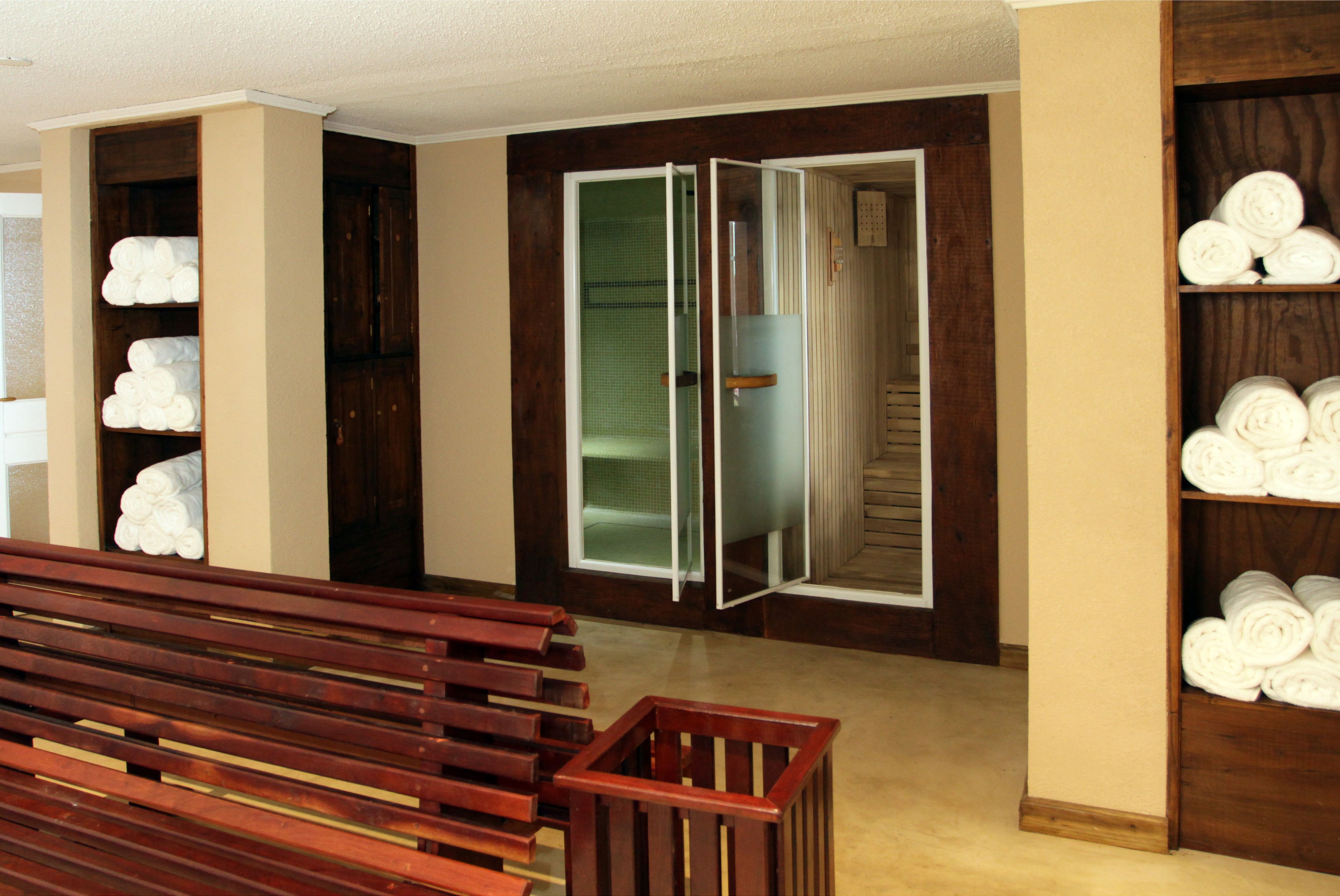 A room with a wooden bench, a wardrobe with towels, and a mirrored closet door.