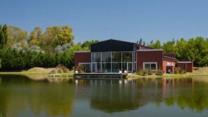 Uma casa moderna com grandes janelas e um cais à beira de um lago tranquilo.