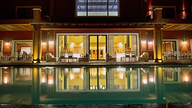Um hotel com piscina, área de estar externa e um hall de entrada espaçoso com portas de vidro.