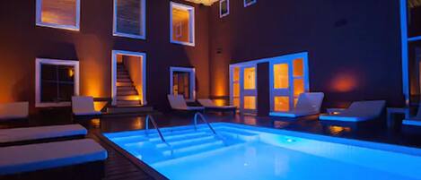 A swimming pool area with lounge chairs and a staircase leading to an upper level.