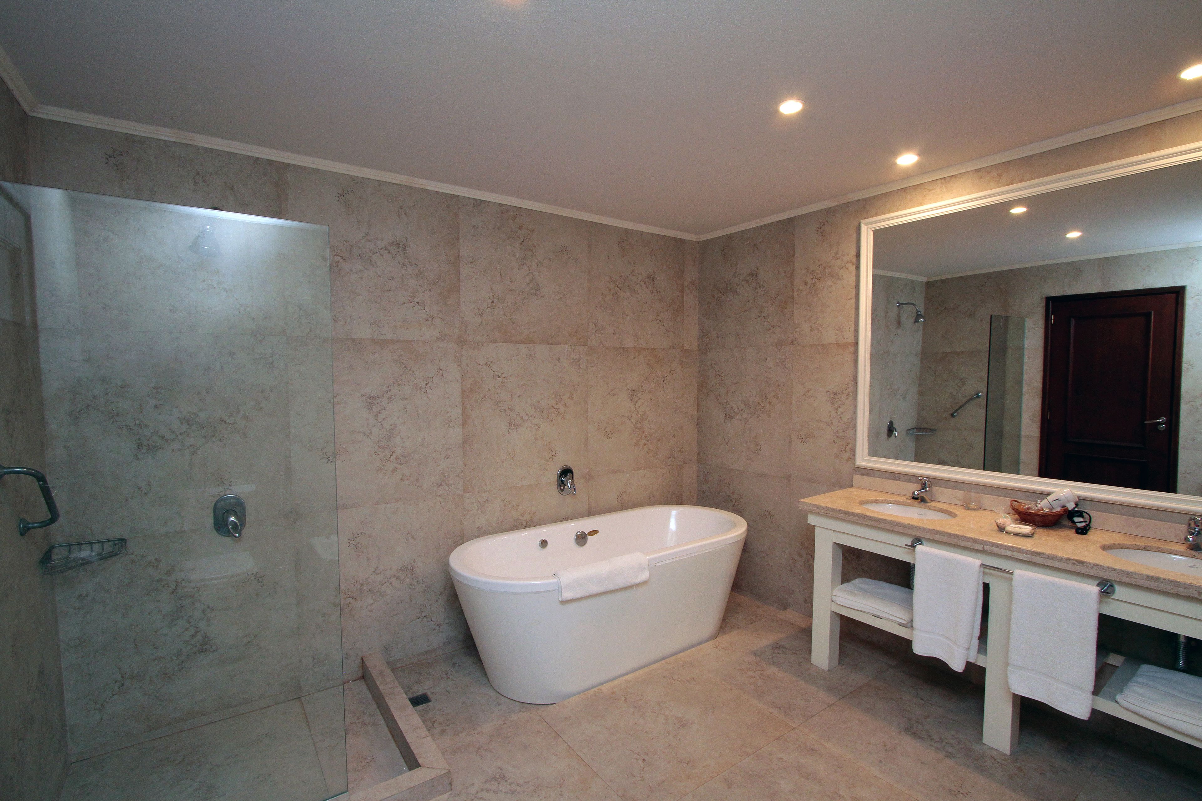 Un baño moderno con una bañera independiente, ducha con cerramiento de vidrio y tocador doble.