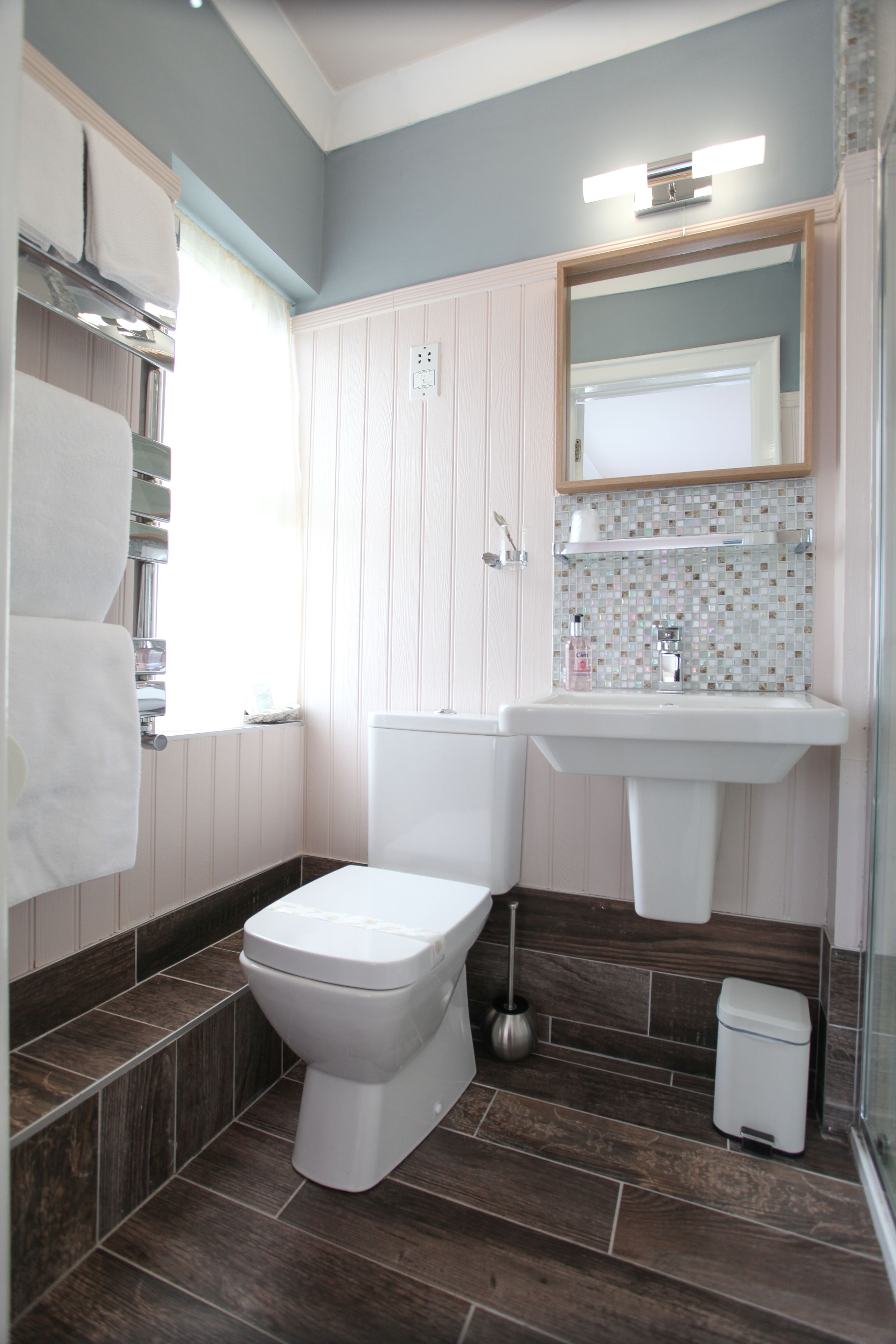 A bathroom with a toilet, sink, and mirror.