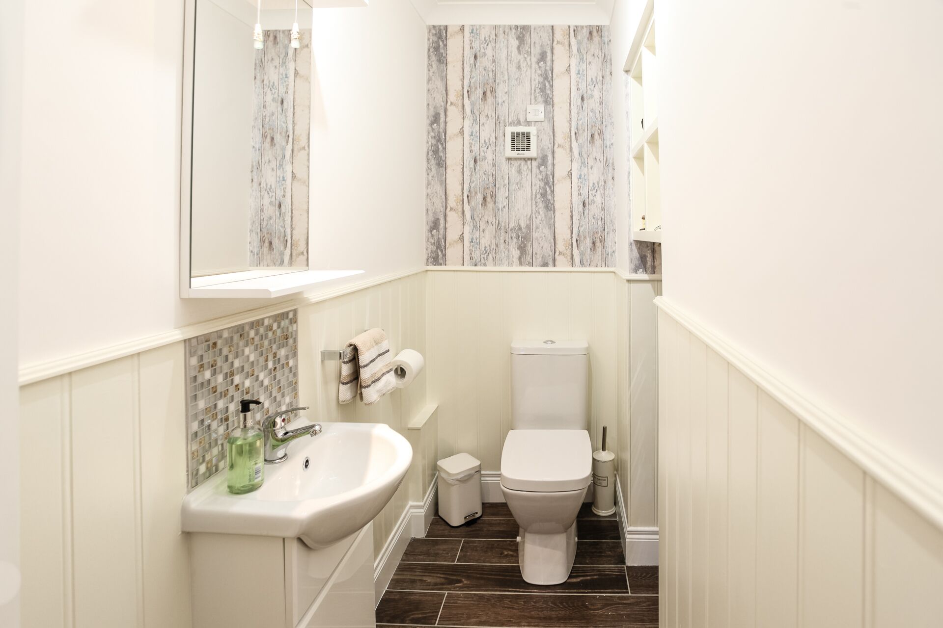 A bathroom with a white sink, toilet, and a mirror above the sink.