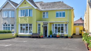 A two-story building with a yellow facade, large windows, and a front entrance. - Anvershiel House (Portrush)