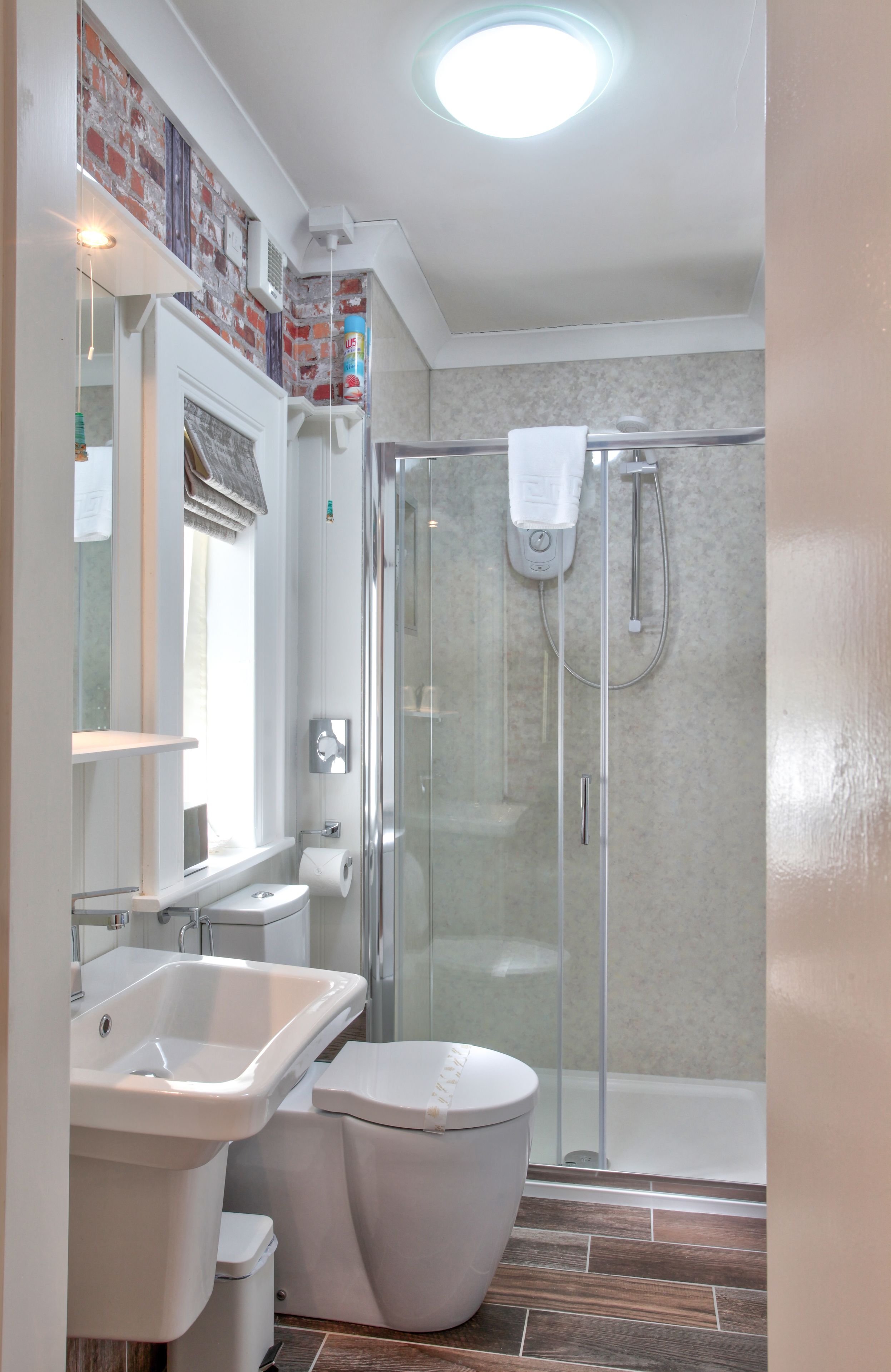 A modern bathroom with a glass-enclosed shower, a white sink, and a toilet.