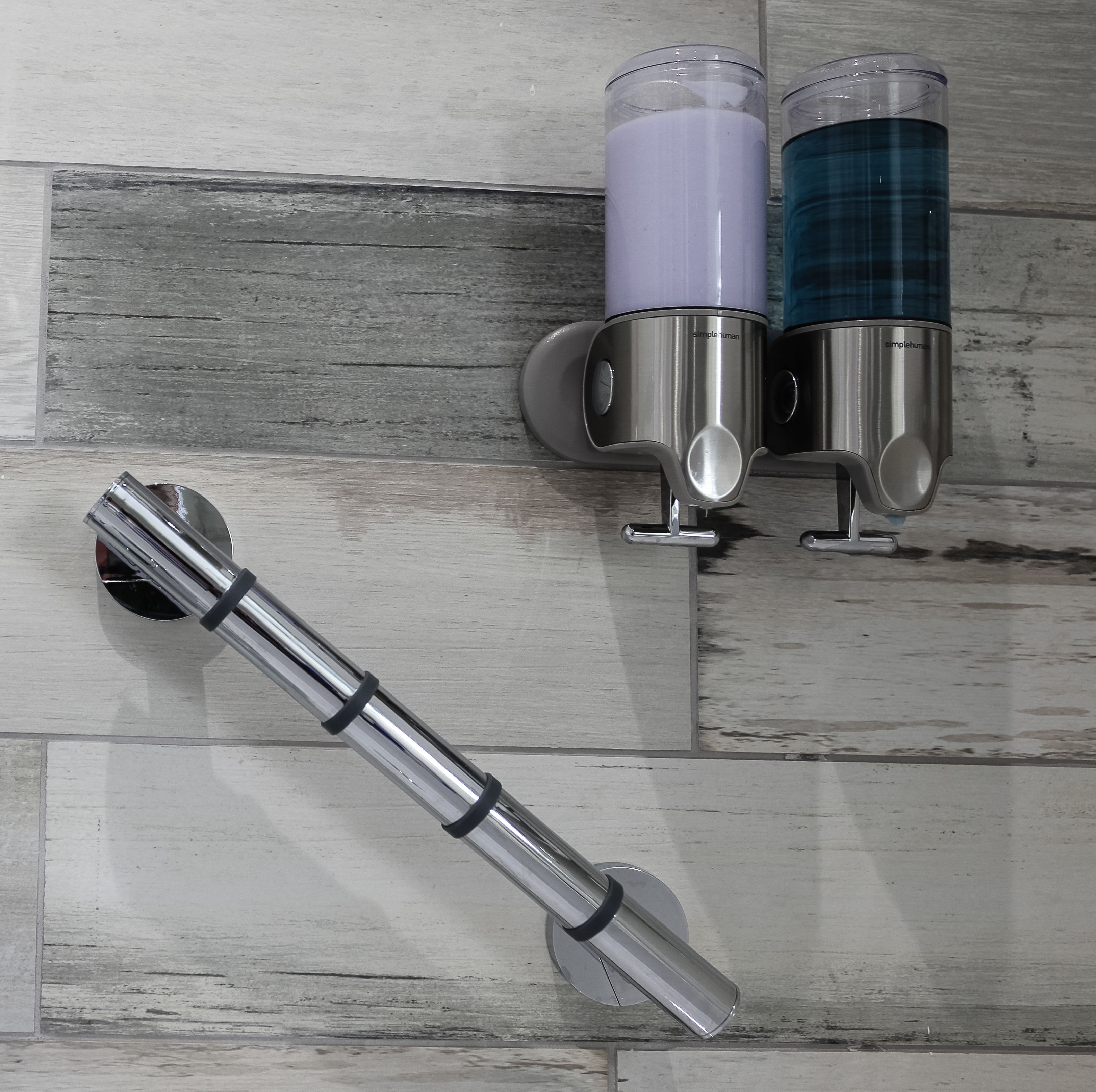 A bathroom with a modern design, featuring a wall-mounted faucet and two soap dispensers.