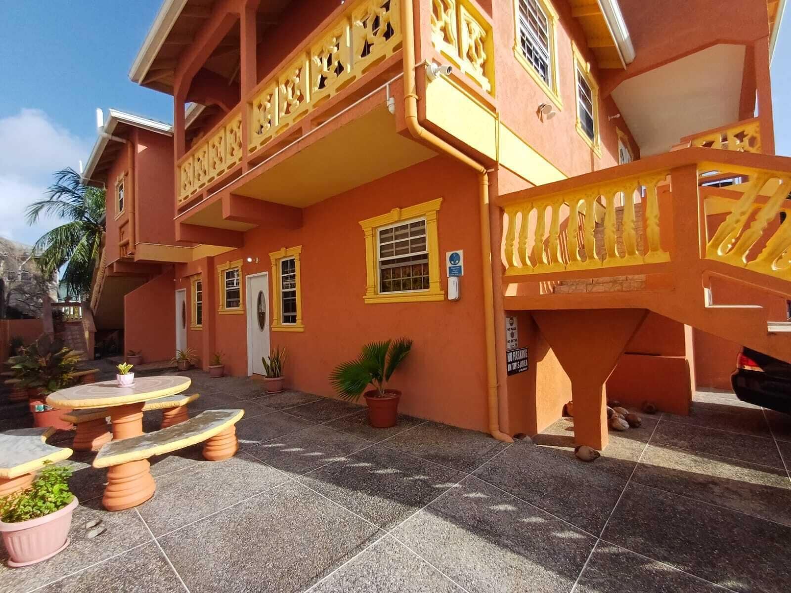 Un bâtiment à la façade jaune, doté de nombreuses fenêtres et d’un escalier avec des rampes jaunes.