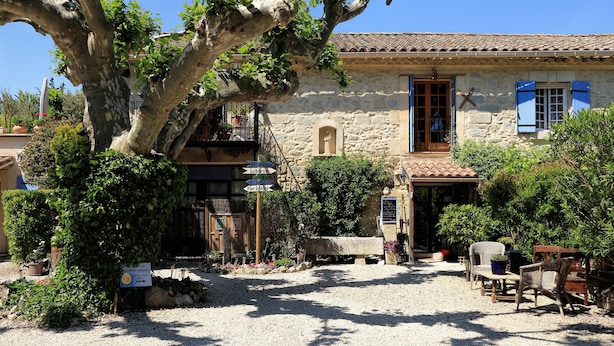 A stone building with a rustic charm, featuring a gravel courtyard and outdoor seating. - Mas Saint Antoine (Rognonas)