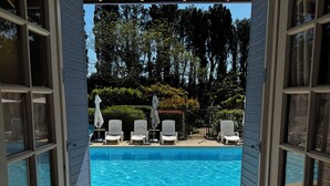An open doorway leading to a swimming pool with lounge chairs and a pergola overhead. - Mas Saint Antoine (Rognonas)