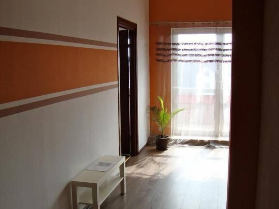 Un pasillo con un banco, una planta en maceta y una puerta que da a otra habitación.