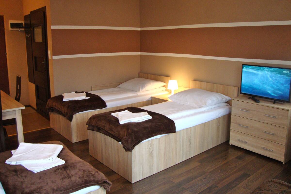 Een hotelkamer met twee bedden, een televisie, een bureau en een stoel.