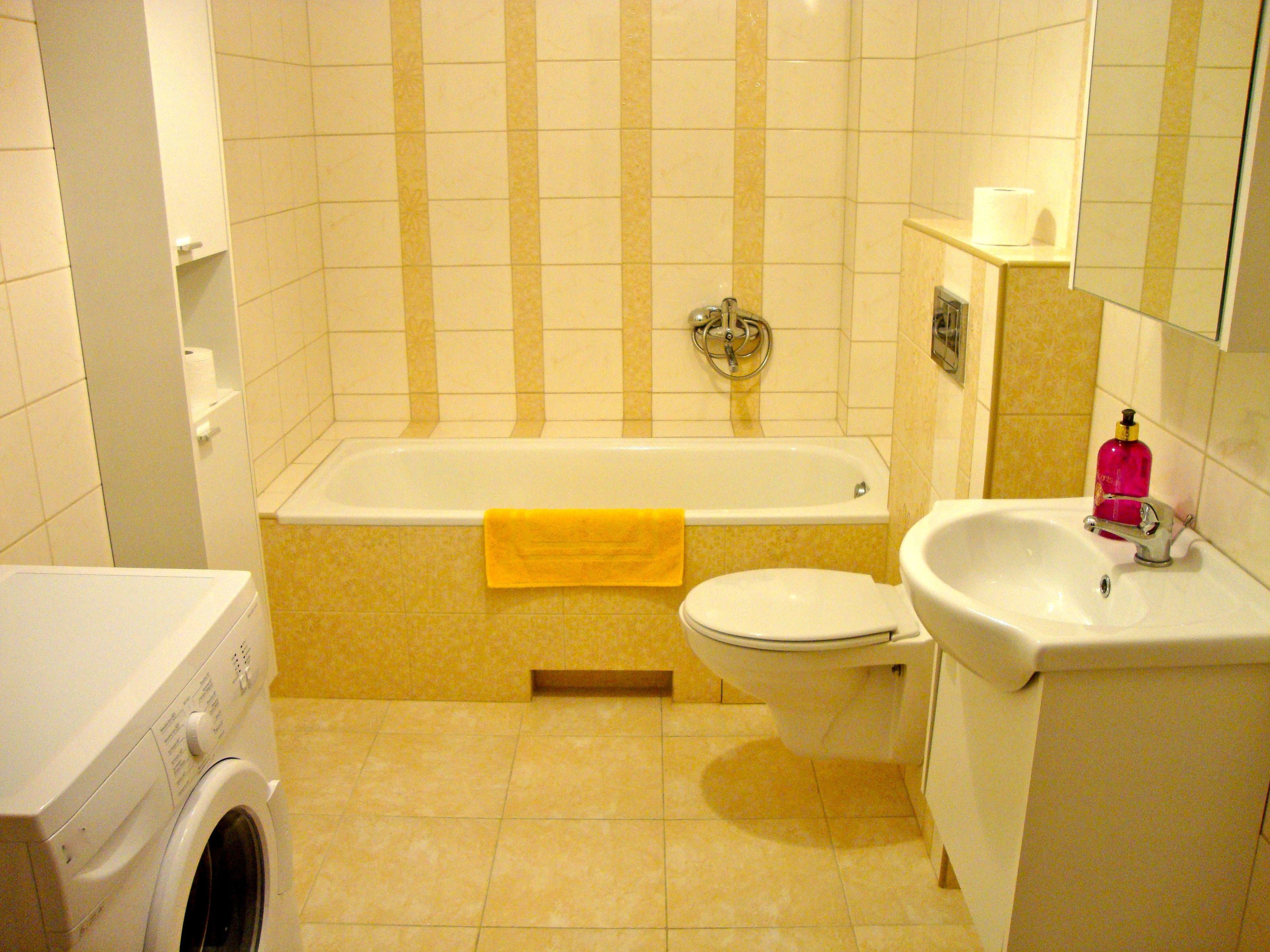 Baño con bañera, inodoro, lavabo y lavadora.