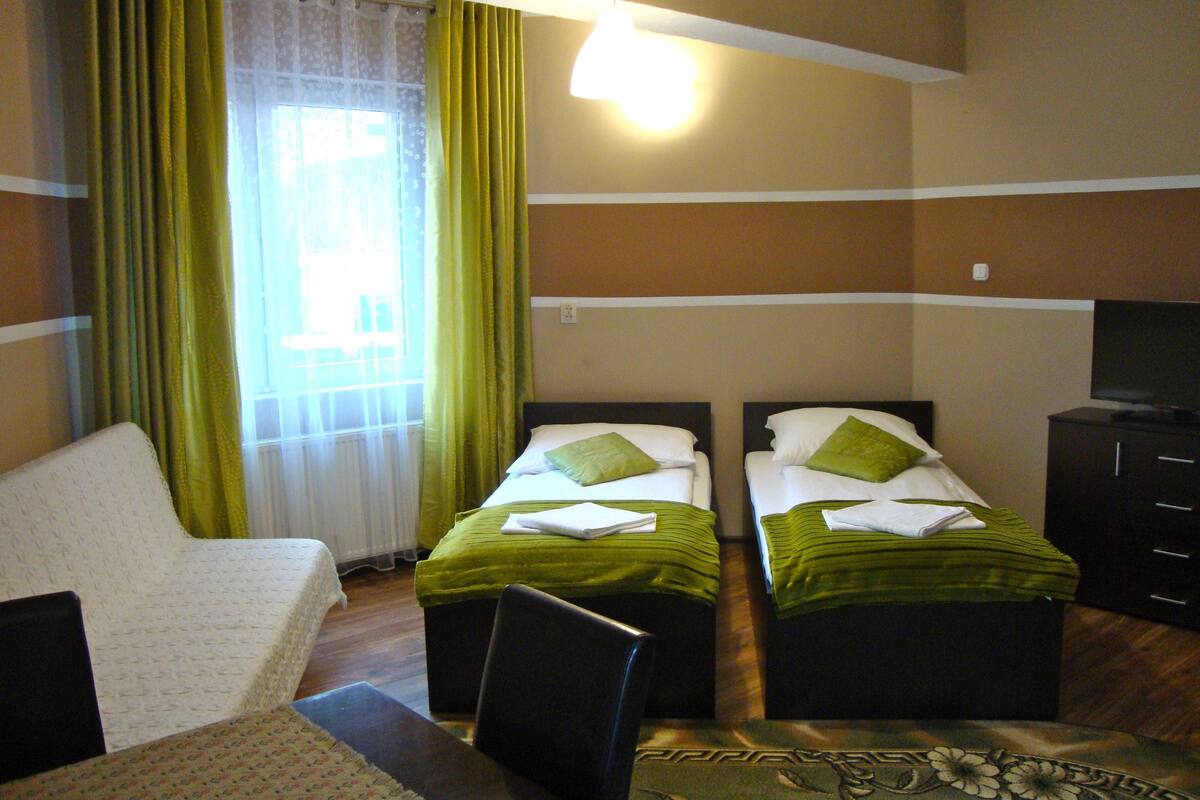 Een hotelkamer met twee bedden, een televisie, een bureau en een stoel.