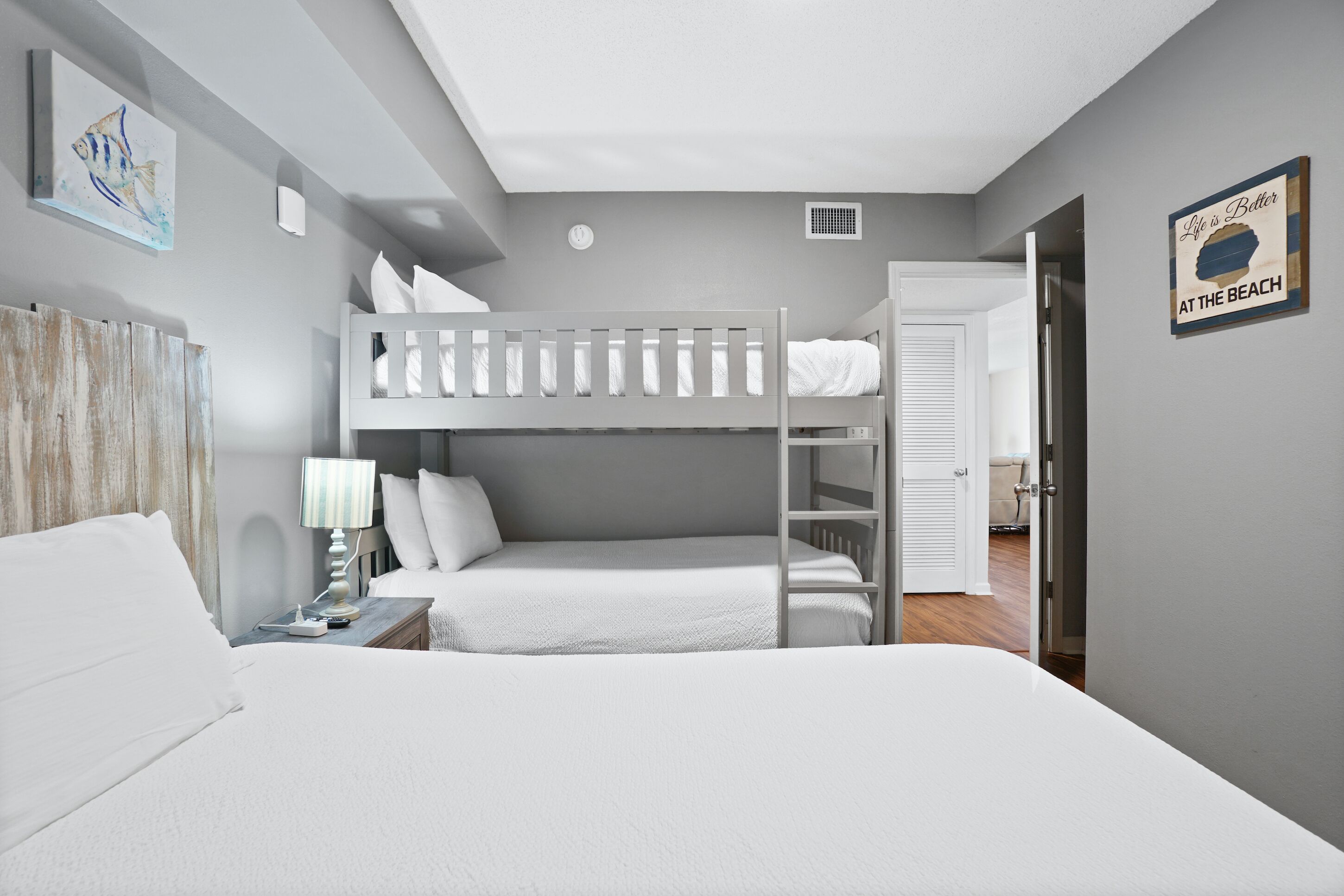 A bedroom with a bunk bed, a bedside table with a lamp, and a wall clock.