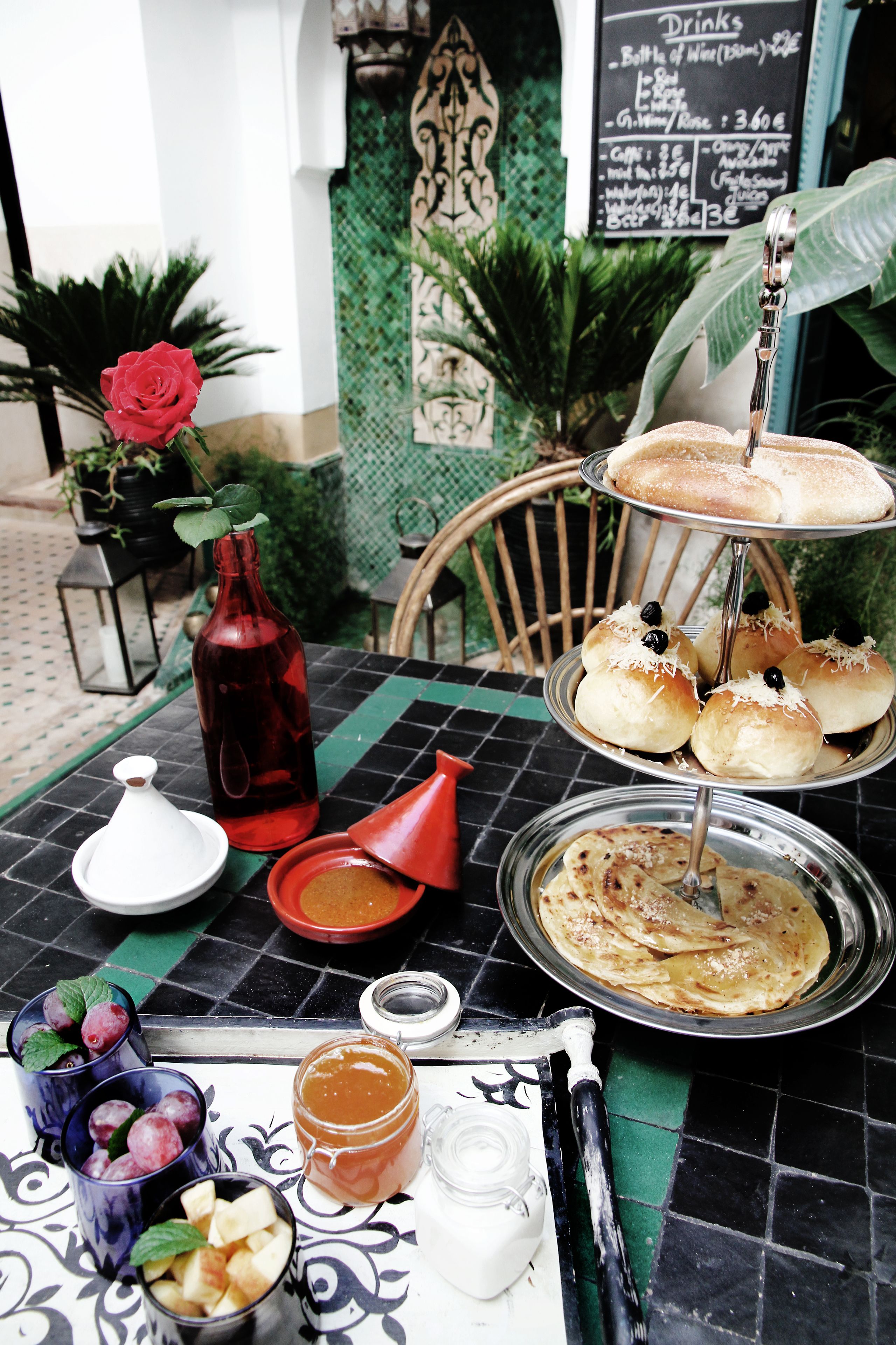 A table with a variety of food items, including pastries, a bottle, and a menu board.