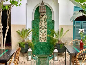 A courtyard with a tiled fountain, potted plants, and outdoor seating. - Riad 11 Zitoune (Marrakech)