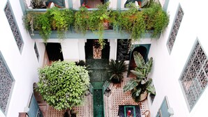 A courtyard with a central seating area, potted plants, and a green awning. - Riad 11 Zitoune (Marrakech)