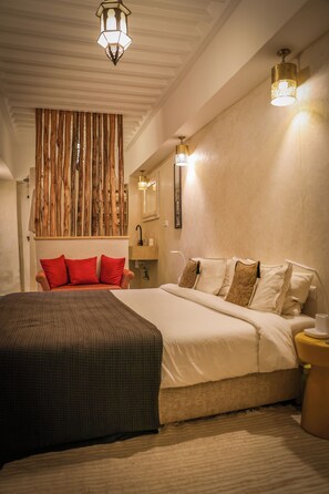 A bedroom with a large bed, a wooden slat wall, a bedside table, and a nightstand. - Riad 11 Zitoune (Marrakech)