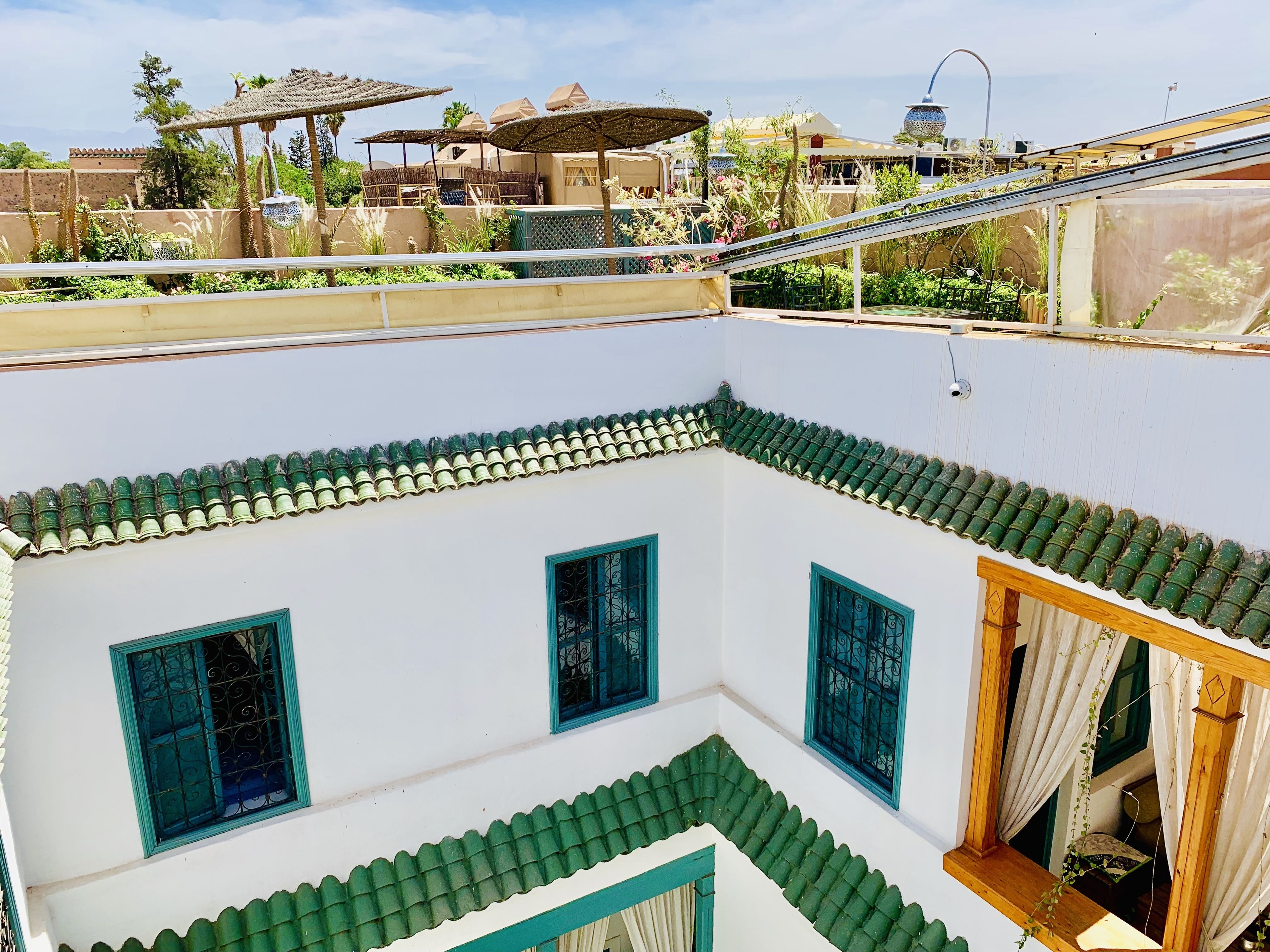 A courtyard with a white building featuring green-tiled roofs and blue window frames.