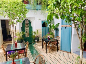 A courtyard with a dining area, a water feature, and a blue door. - Riad 11 Zitoune (Marrakech)