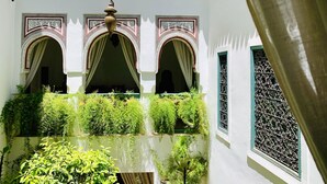 A courtyard with arches, a fountain, and lush greenery. - Riad 11 Zitoune (Marrakech)