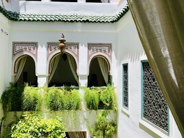 Un patio con arcos, una fuente y abundante vegetación.