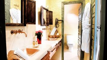 Une salle de bain avec un meuble-lavabo en bois, un miroir, un porte-serviettes, un lavabo et des toilettes.