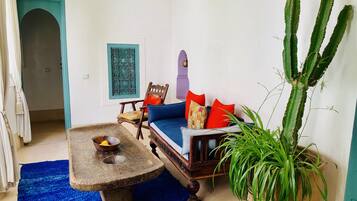 A cozy living room with a blue sofa, wooden coffee table, and a cactus plant.