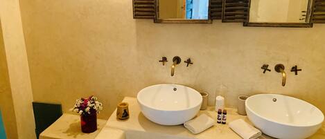 A bathroom with two sinks, a mirror, and a window with shutters.