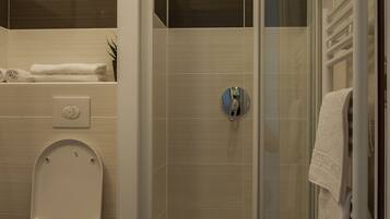 A modern bathroom with a glass-enclosed shower, a toilet, and a towel rack.