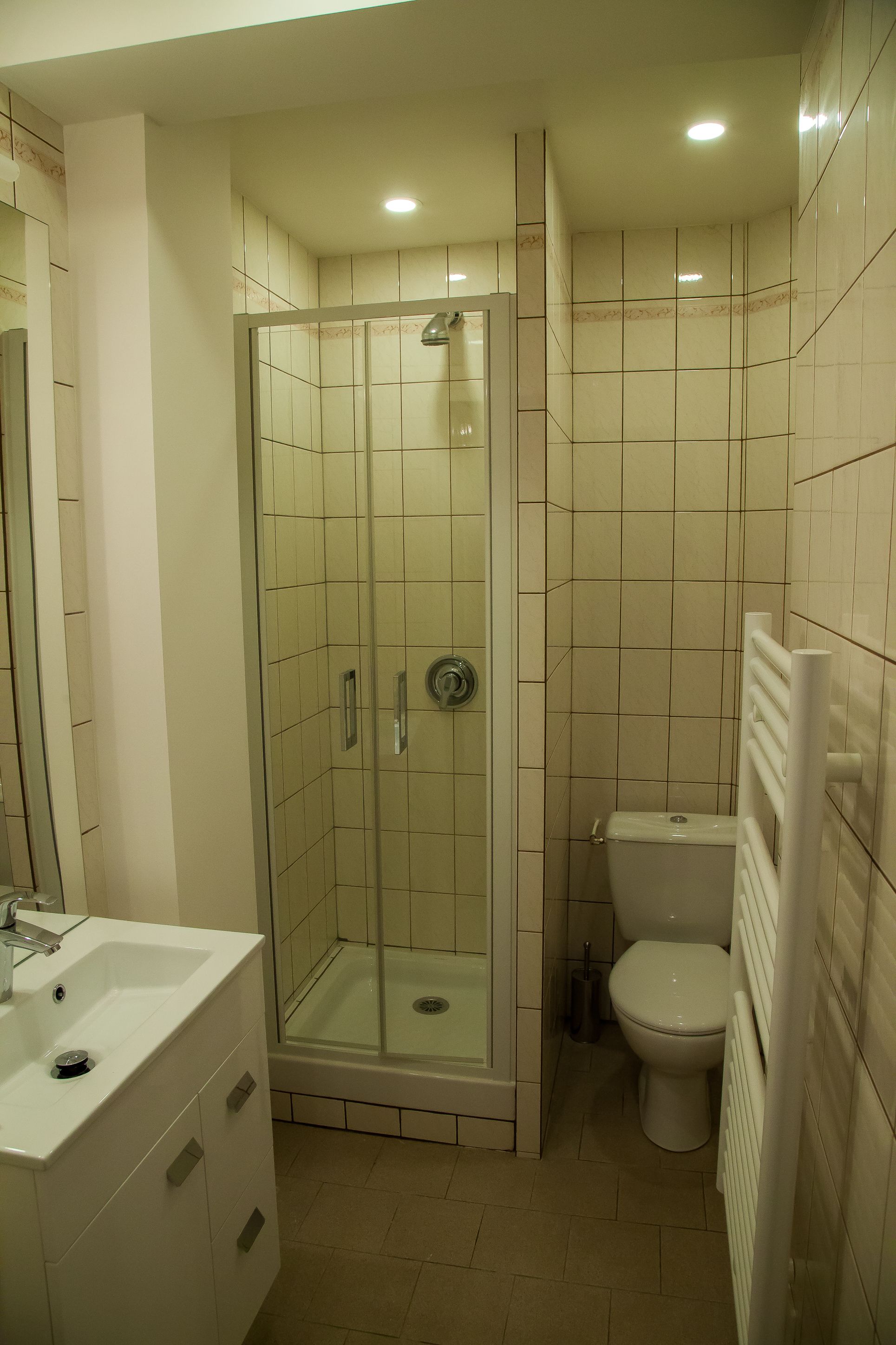 A bathroom with a glass-enclosed shower, a white sink, and a toilet.