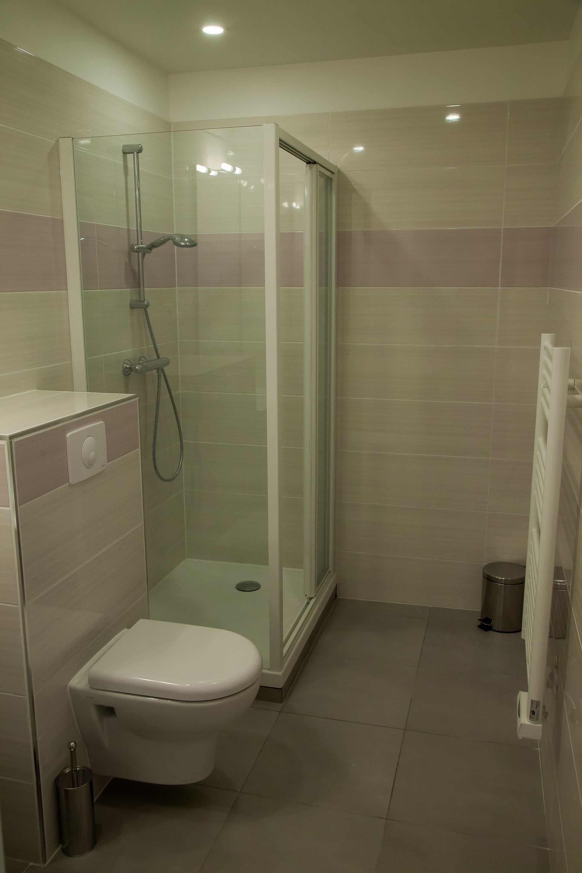 Ein kleines Badezimmer mit Toilette, einer Duschkabine und einem Heizkörper.