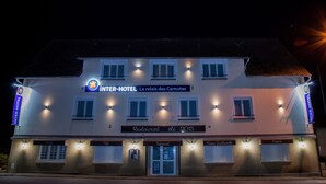 A multi-story building with illuminated signs for "INTER-HOTEL" and "Le relais des Carnutes."