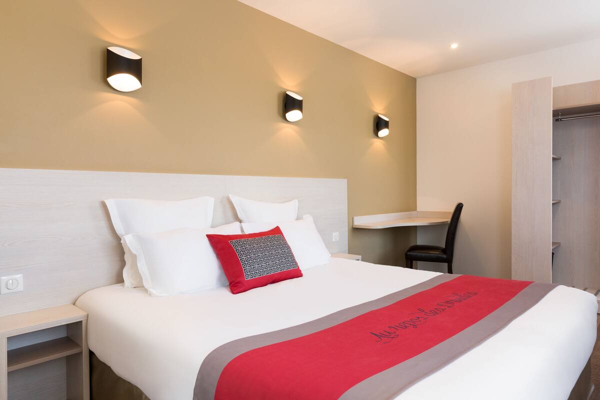 Una habitación de hotel con cama, mesita de noche, silla y armario.