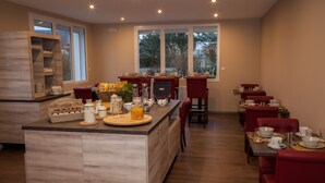 A spacious dining area with a central island, red upholstered chairs, and a variety of table settings.